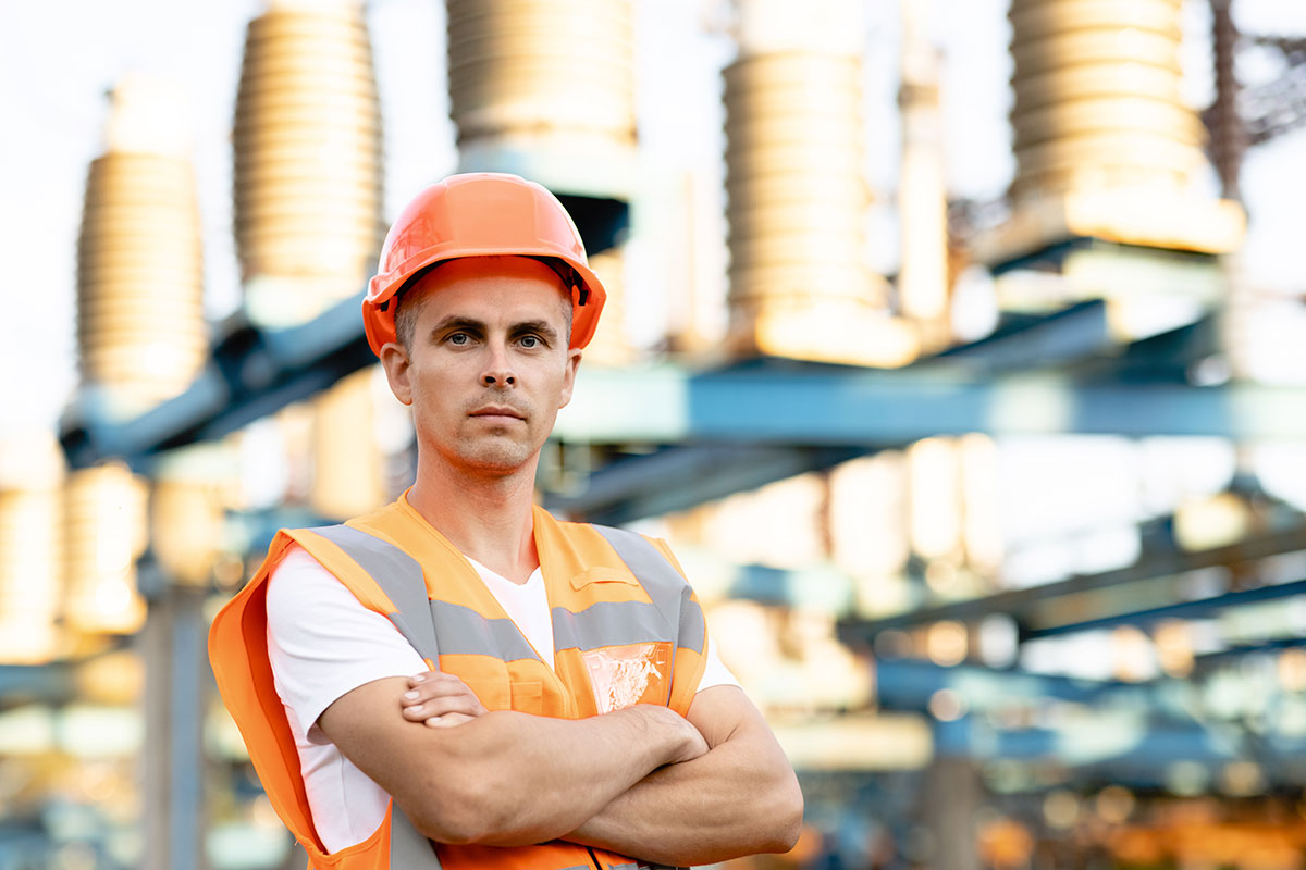 engineer-worker-in-uniform-and-helmet-standing-near-high-voltage-substation
